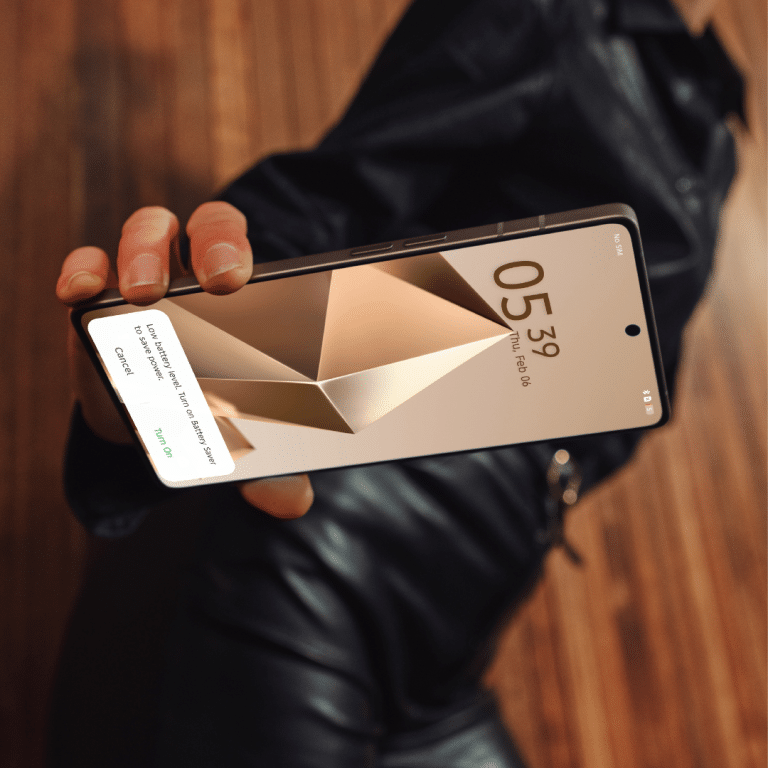 סמארטפון Infinix Note 50 Pro ביד, מציג מסך קמור ואלגנטי עם התראה על סוללה נמוכה.