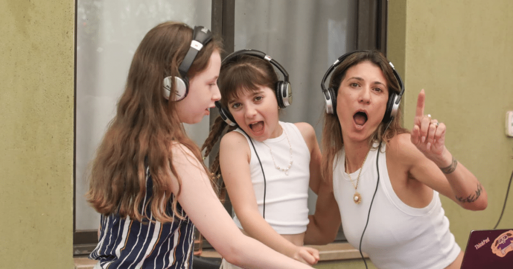 ילדים ואמא משתתפים בהפעלת DJ חווייתית עם אוזניות ועמדת מוזיקה במסגרת פעילות Follow The Beat