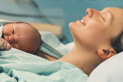 אישה יולדת מחזיקה תינוק בזרועותיה בחדר לידה בבית חולים - רגע הלידה המרגש