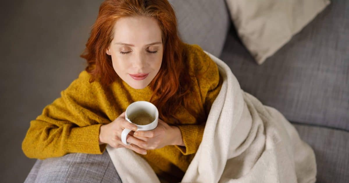 Young,Woman,Relaxing,On,A,Sofa,With,Ca,Mug,Of