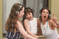 ילדים ואמא משתתפים בהפעלת DJ חווייתית עם אוזניות ועמדת מוזיקה במסגרת פעילות Follow The Beat