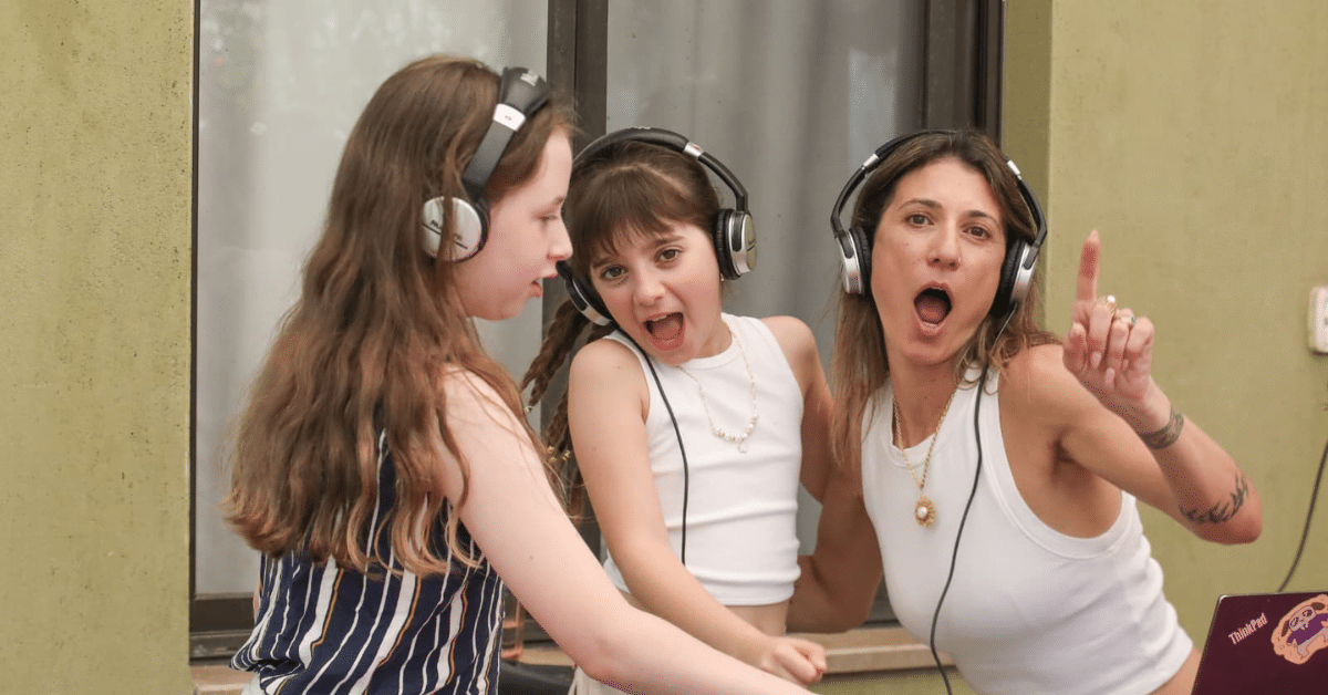 ילדים ואמא משתתפים בהפעלת DJ חווייתית עם אוזניות ועמדת מוזיקה במסגרת פעילות Follow The Beat